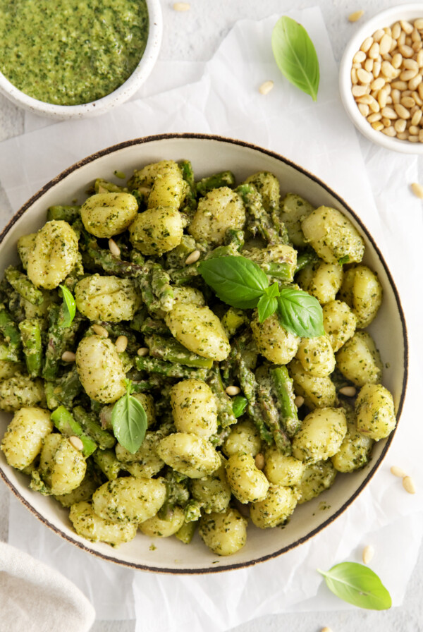 Pesto gnocchi served in a bowl garnished with basil leaves.