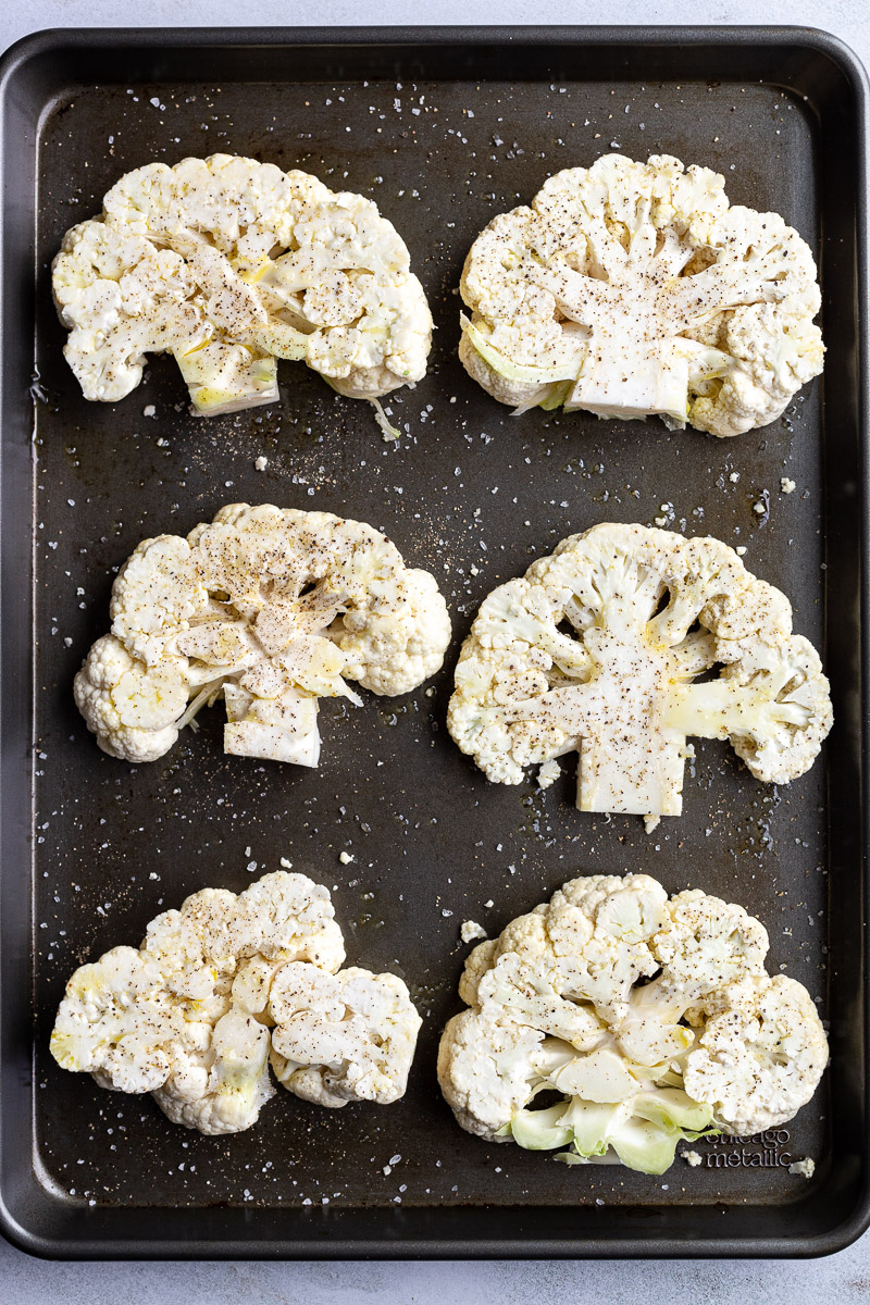 Raw cauliflower on a sheet pan before being cooked.