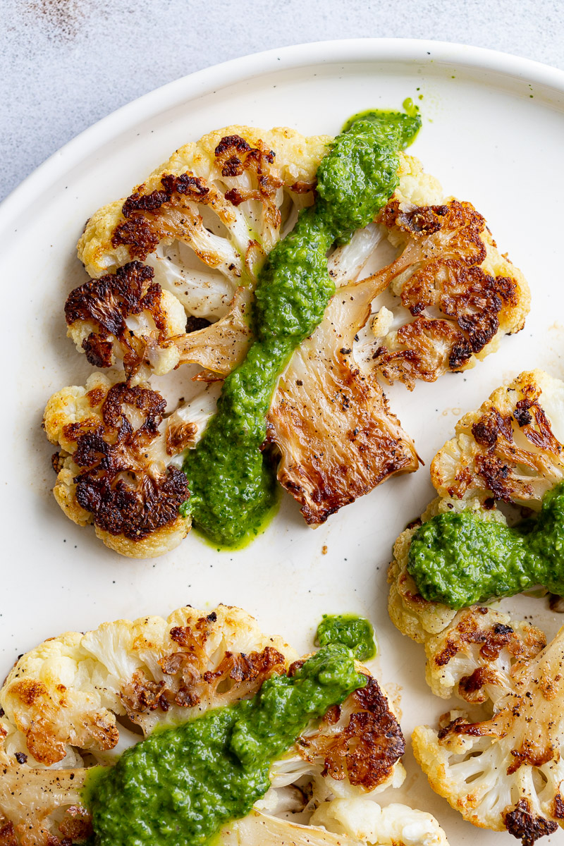 Slice of roasted cauliflower with green sauce.