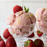 Strawberry Shortcake Ice Cream scooped into a glass ice cream dish.