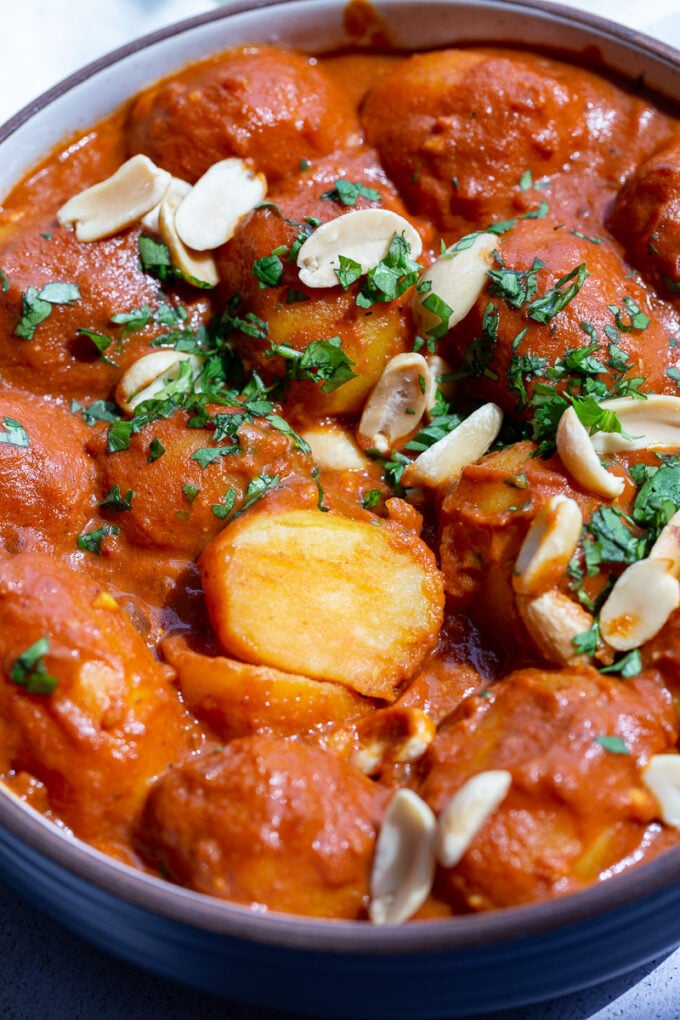 Sliced potato in a tomato sauce garnished with cilantro.