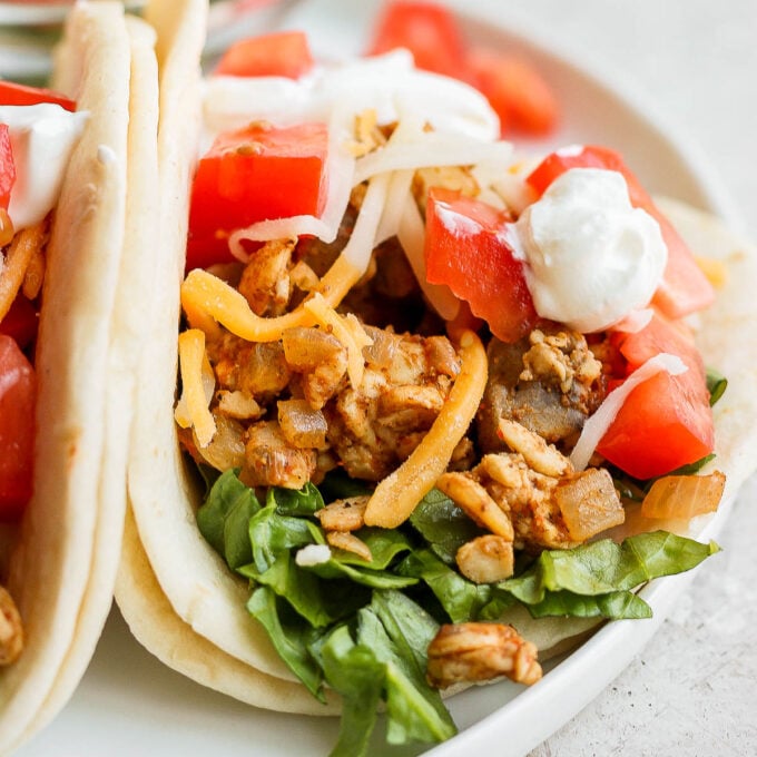 tempeh tacos topped with tomato, cheese, and sour cream