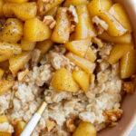 Bowl of oatmeal topped with cinnamon apples.