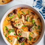 Soup made with tofu and mushrooms in a white bowl.