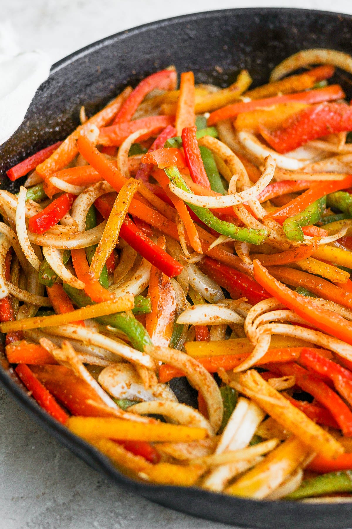 Fajita veggies cooking in a cast iron skillet.