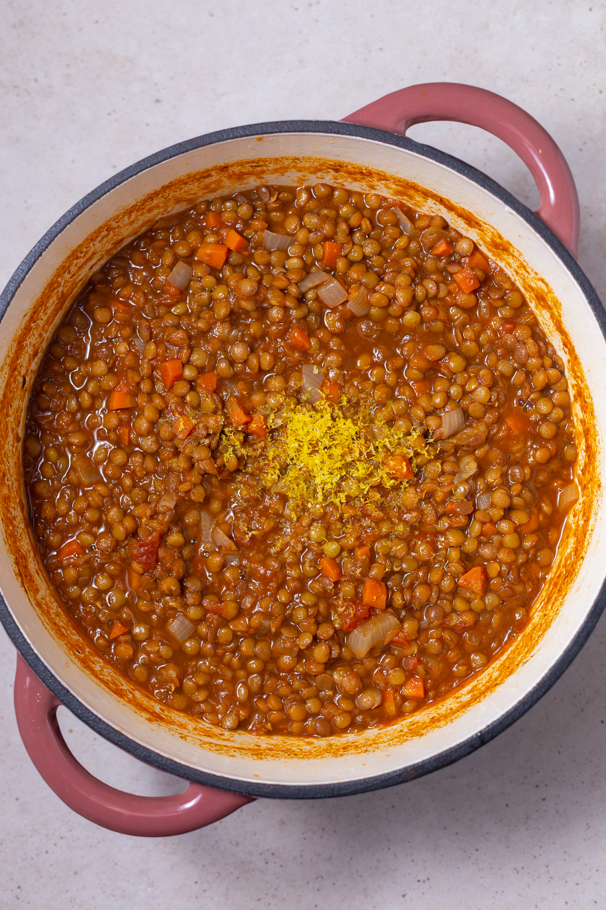 ingredients for lentil soup in a pot. lemon zest is on top