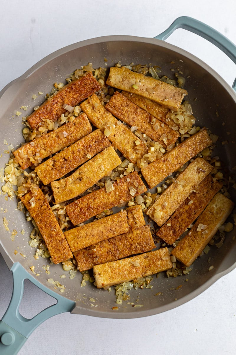 Tofu cooking in a large skillet.