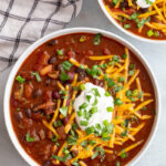 Instant pot chili topped with shredded cheese, sour cream and green onions.