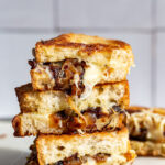 Caramelized Onion grilled cheese stacked on top of itself with cheese and onion oozing out