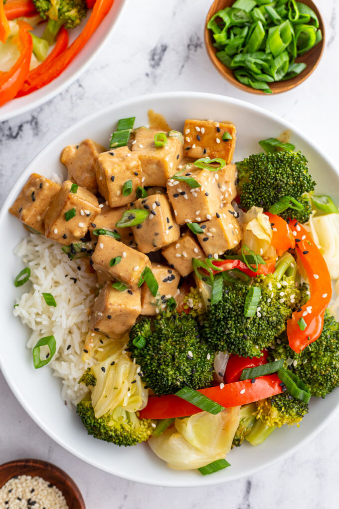 Peanut sauce tofu served over rice with broccoli and bell pepper.