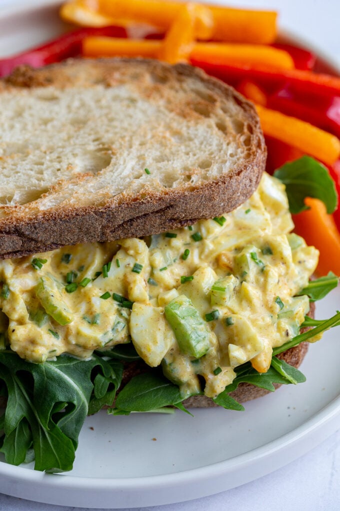 curried egg salad on toast with arugula on a plate
