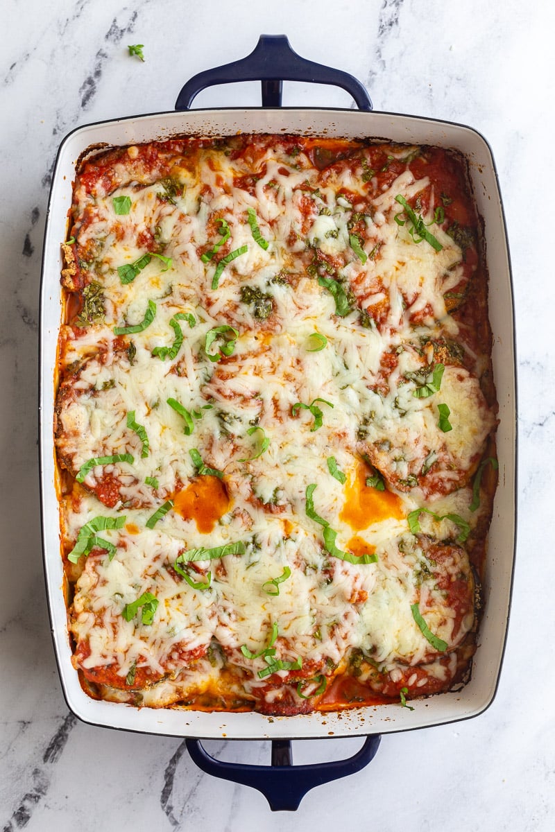 Eggplant slices layered with cheese and marinara sauce in a white casserole dish.