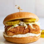 tofu "chicken sandwich on a bun with mayo, cabbage and pickles and a toothpick in the center