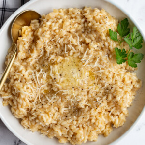 Risotto in a white bowl garnished with fresh parsley.