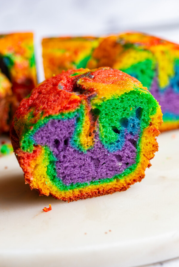 slice of rainbow bundt cake with the rest of the cake behind it