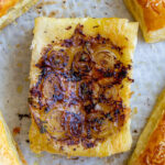 french onion tarts on a baking tray lined with parchment paper