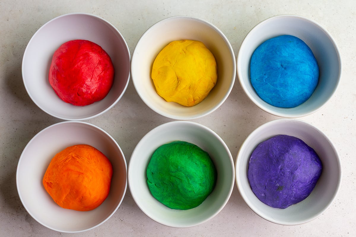 6 bowls of bread dough, each a different color: red, yellow, blue, orange, green, purple