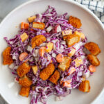 2 wide bowls of cabbage and carrot salad that are topped with diced buffalo wings