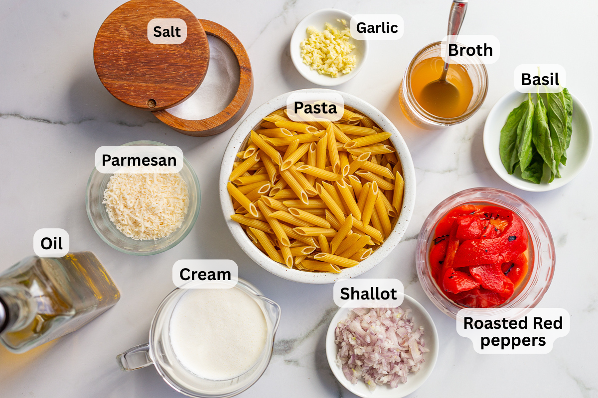 Labeled ingredients for roasted red pepper pasta including penne pasta, roasted red peppers, heavy cream, parmesan, shallot, garlic, vegetable broth, basil, oil, and salt