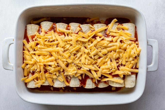 unbaked enchiladas with cheese on top.