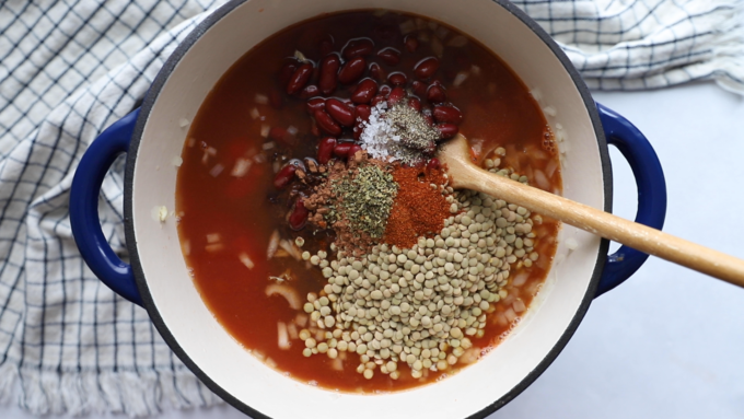 how to make lentil chili: all of the ingredients being added into the pot