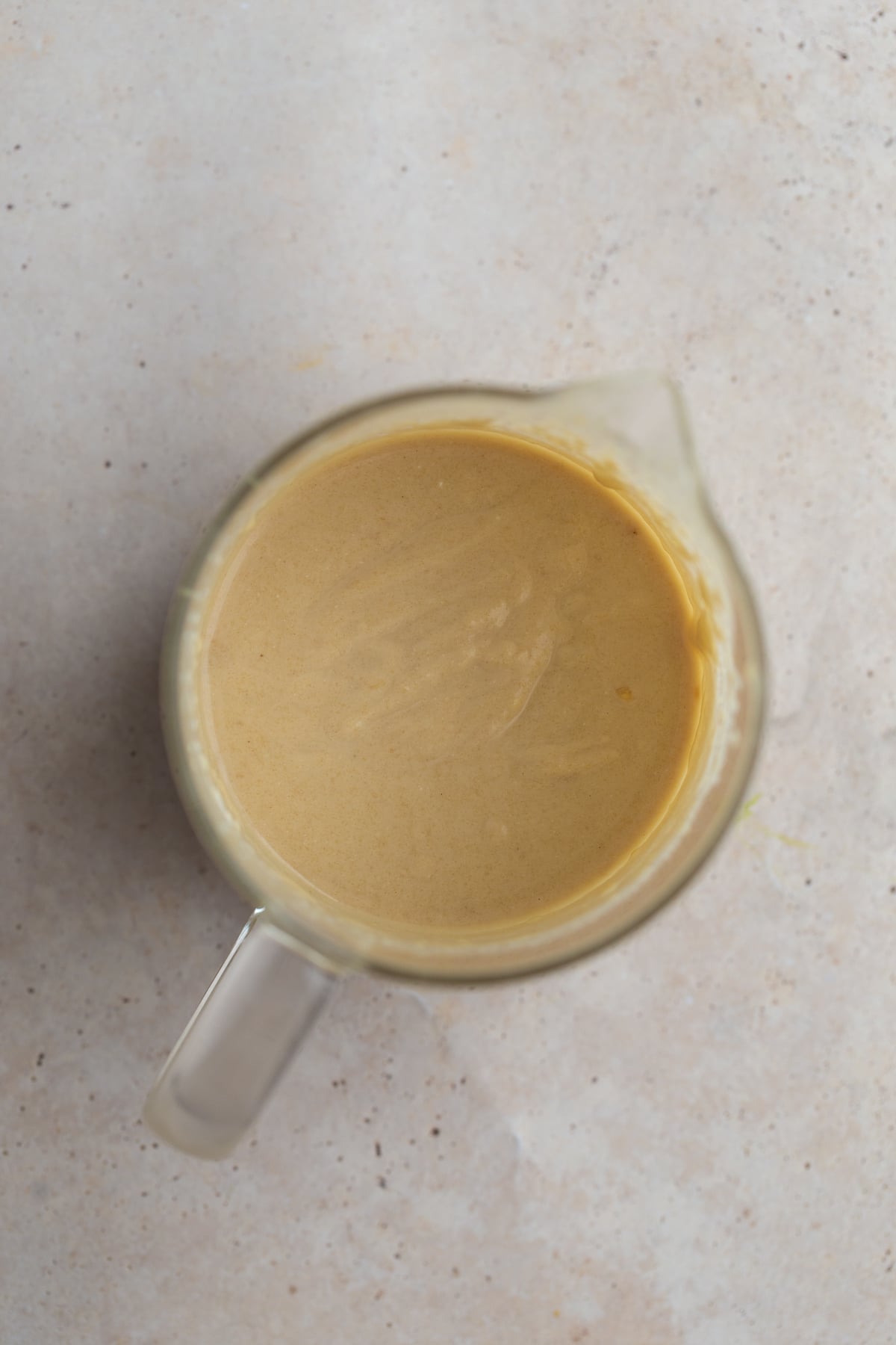 Smooth and creamy tahini sauce in a clear glass container, ready for drizzling.