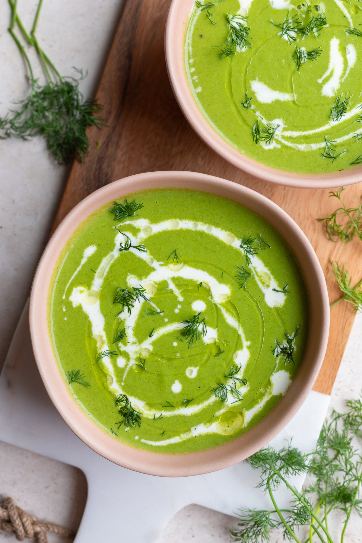 green goddess soup that's vibrant green in a pink bowl with a cream drizzle