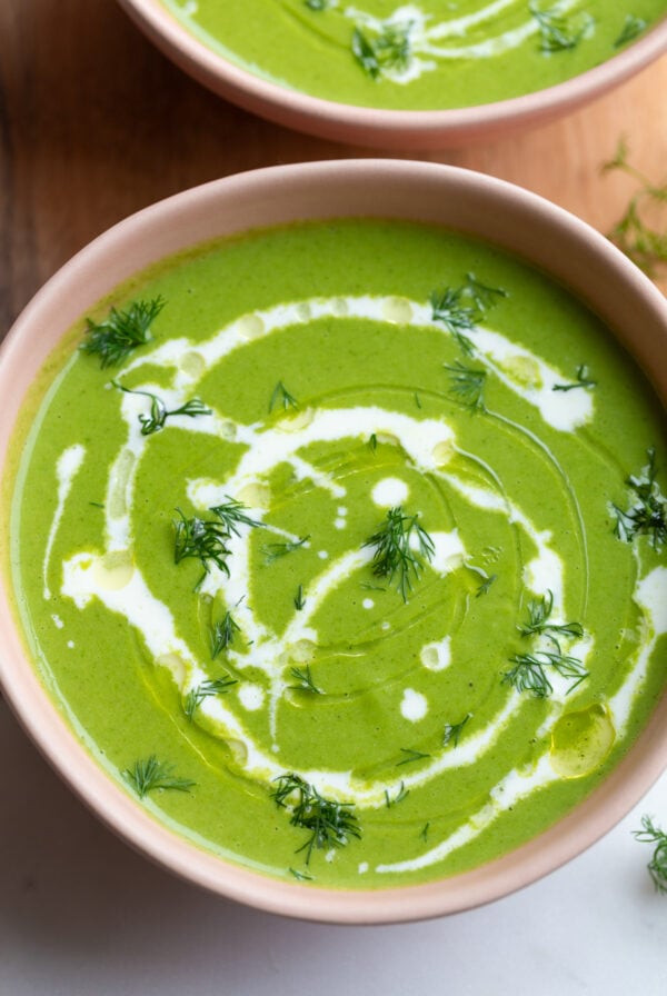 green goddess soup that's vibrant green in a pink bowl with a cream drizzle