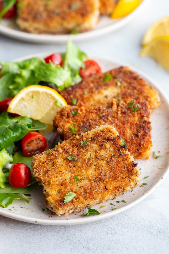 Tofu cutlets served with a salad on a white plate.