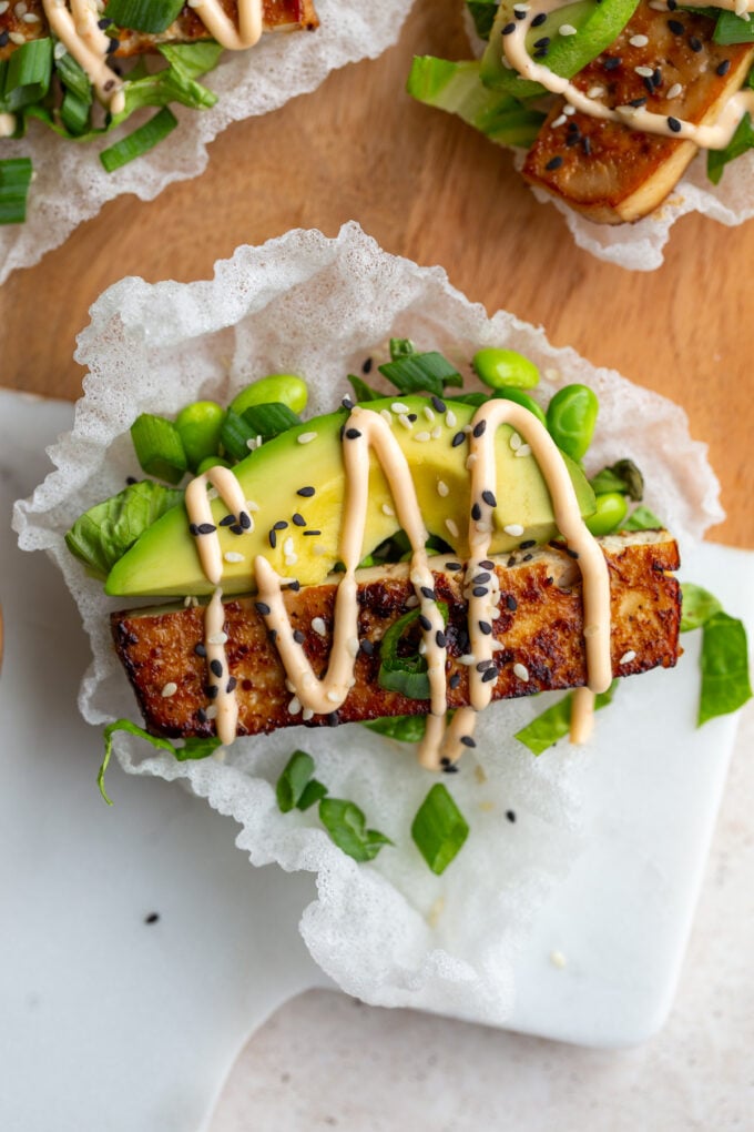 rice paper tacos topped with lettuce, avocado and tofu slices. drizzled with spicy mayo