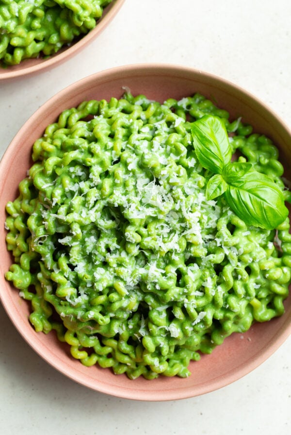Green pasta garnished with basil leaves.