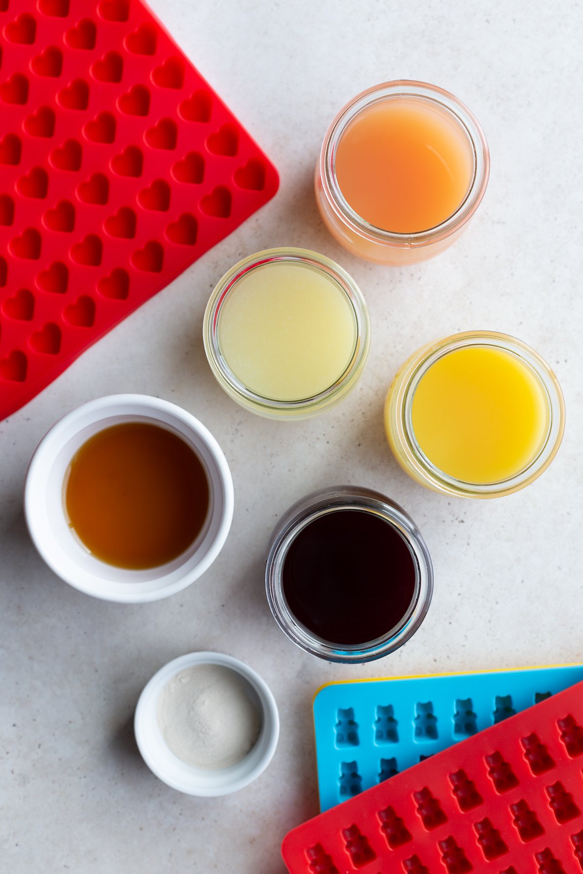 Small bowls with fruit juice, agar agar powder and maple syrup near candy molds.