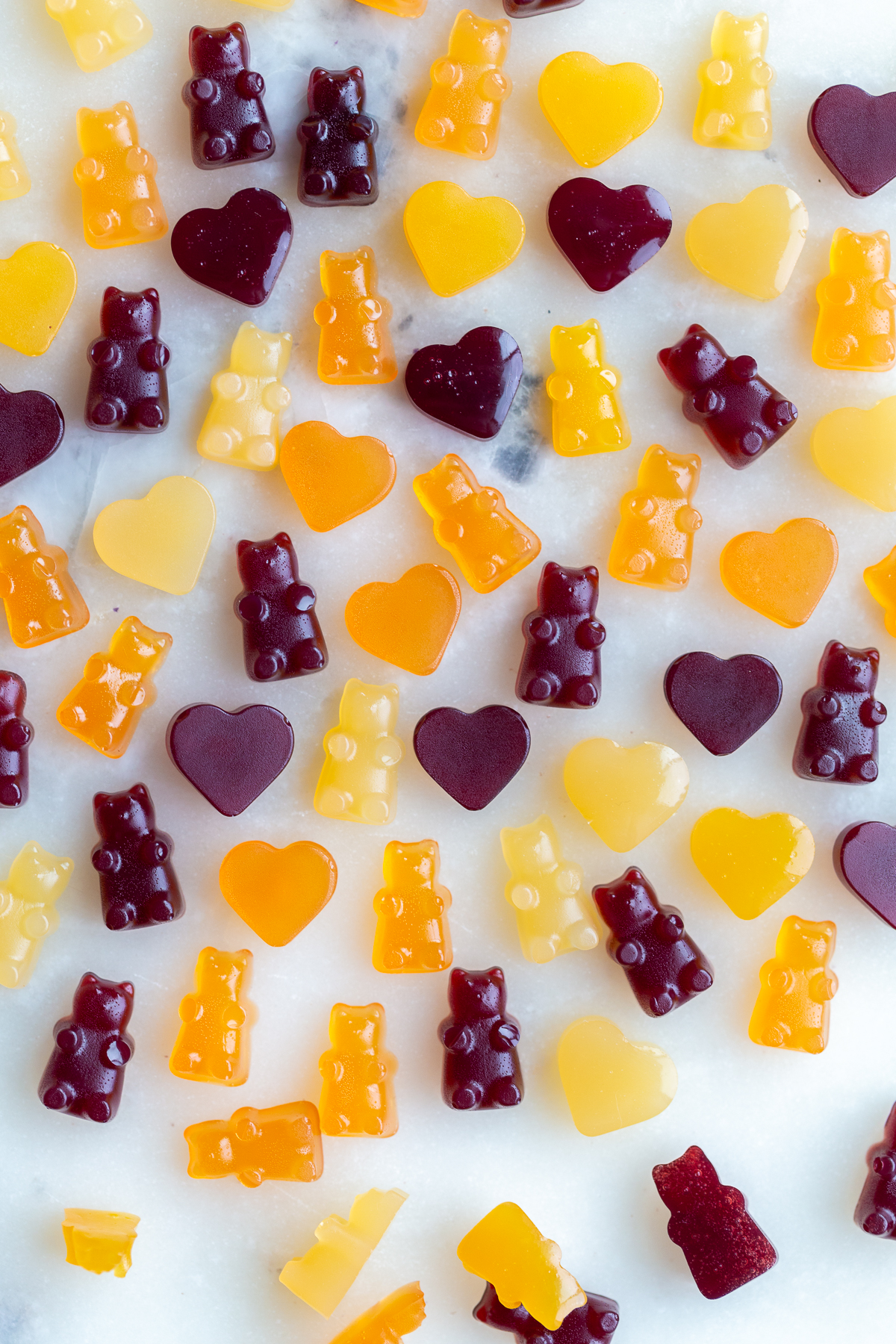 Gummy bears and hearts on a marble counter.