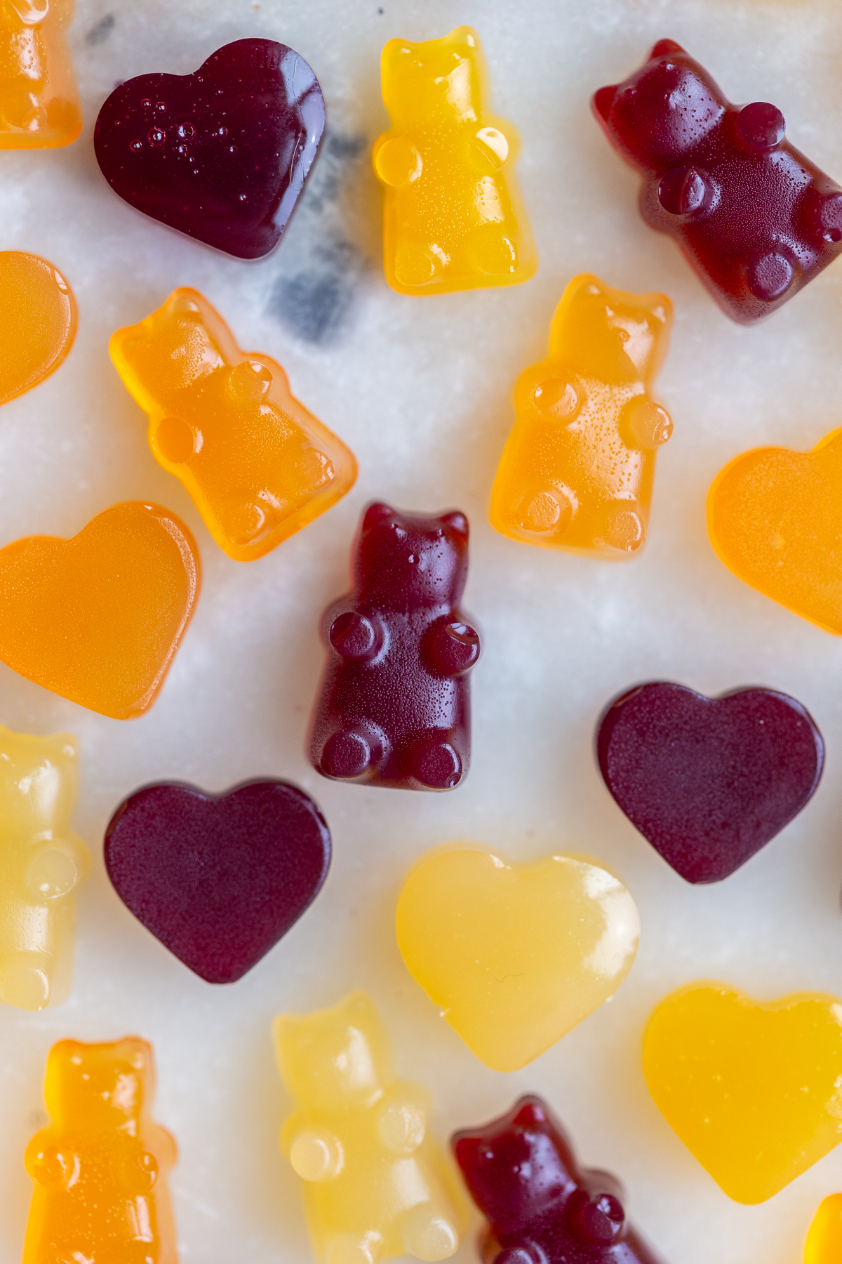 Vegan gummy bears that are orange, yellow and dark red.