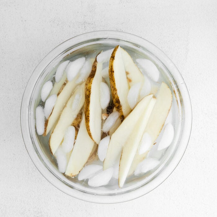raw potato slices in an ice bath