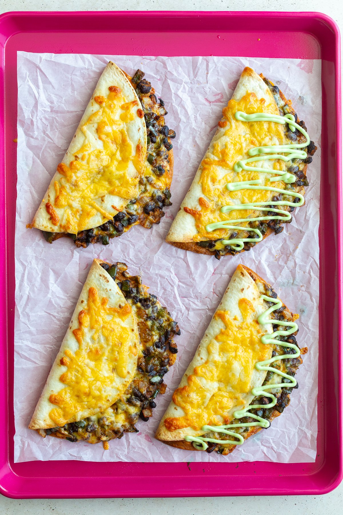cheesy black bean tacos on a red baking sheet