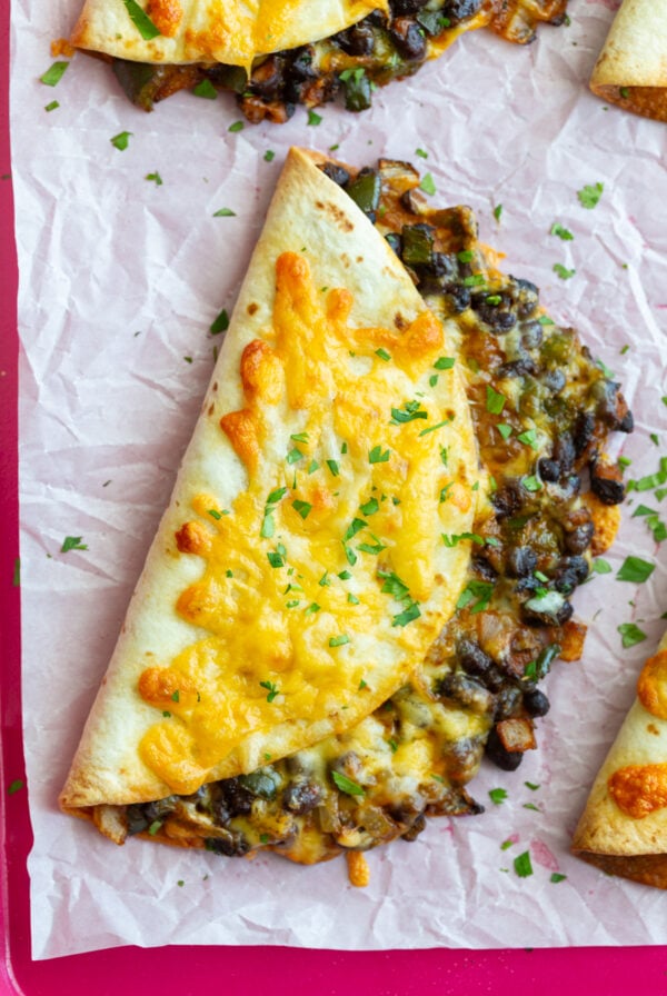 crispy black bean tacos with melted cheese on the outside. sprinkled with cilantro