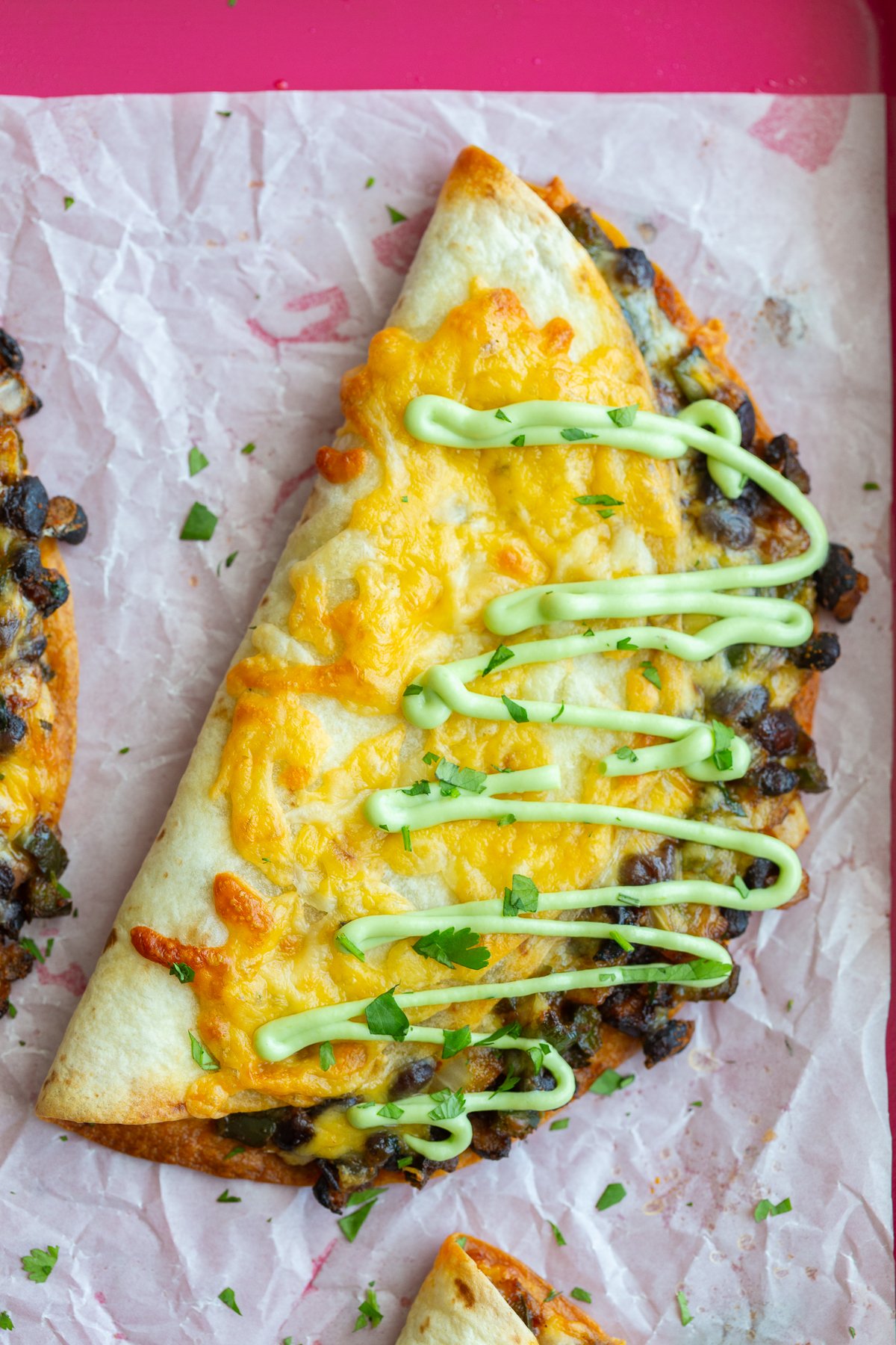 crispy black bean tacos with melted cheese on the outside. sprinkled with cilantro and a drizzle of green sauce