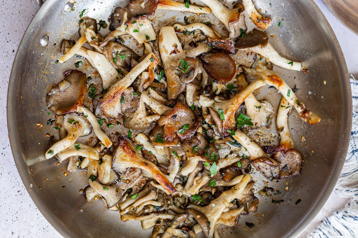 Sautéing oyster mushrooms in a pan.