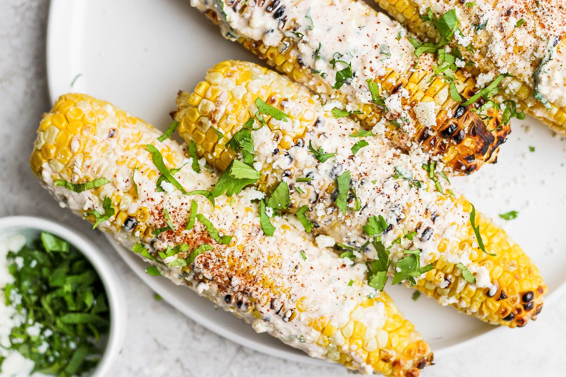 mexican street corn on a white plate topped with cilantro and cotija
