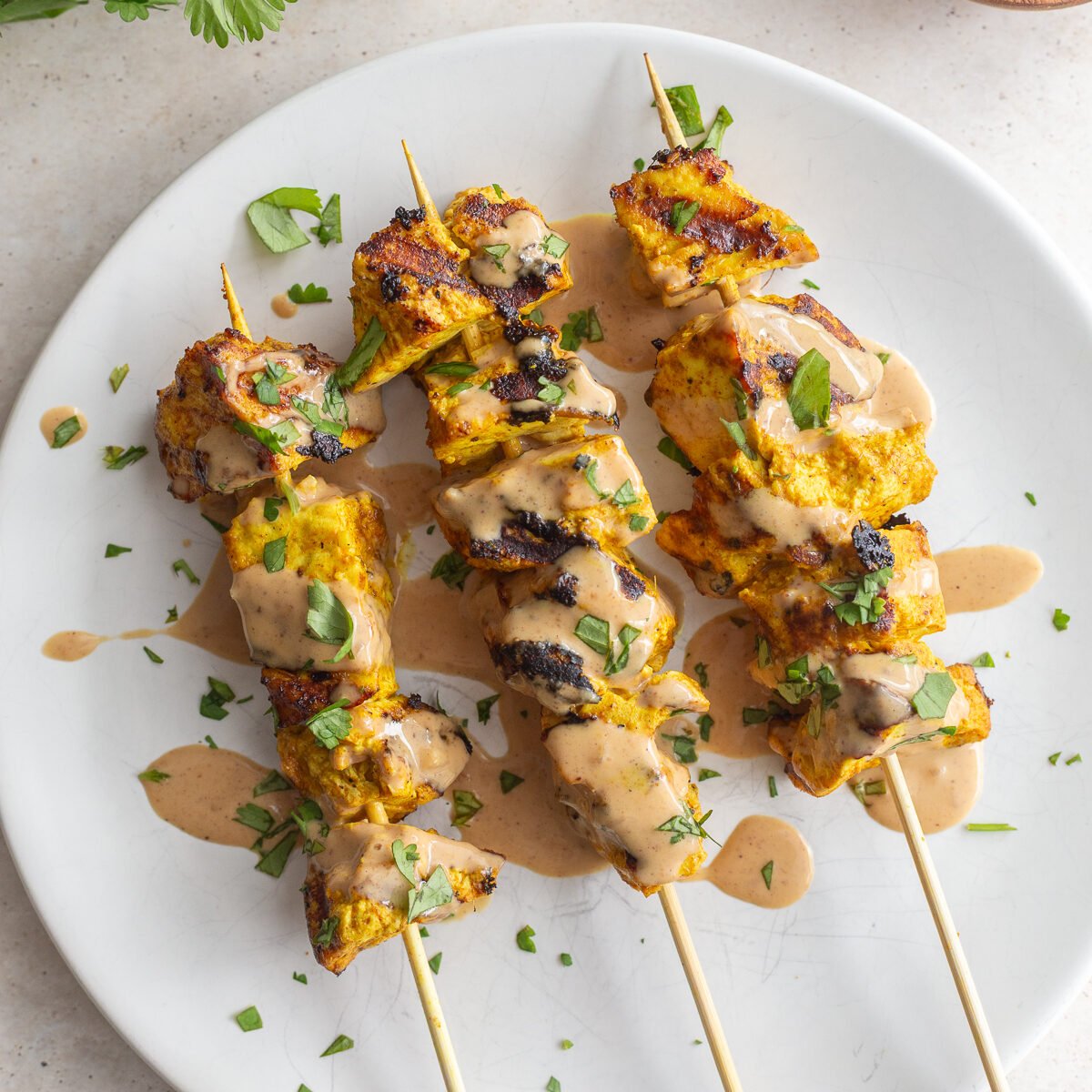 Tofu satay drizzled with peanut sauce and garnished with fresh cilantro.