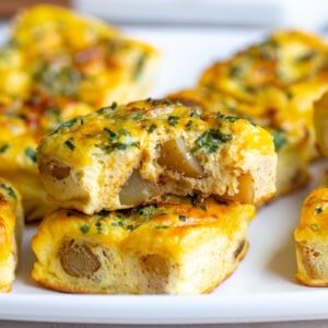 potato chive egg bites stacked on top of each other with one having a bite taken out