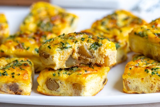 potato chive egg bites stacked on top of each other with one having a bite taken out
