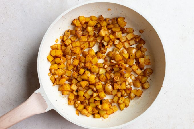 sauteed potato hashbrowns in a large white skillet