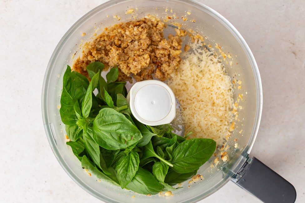 how to make pesto step 2: food processor that has processed pinenutes in it along with fresh basil and Parmesan cheese
