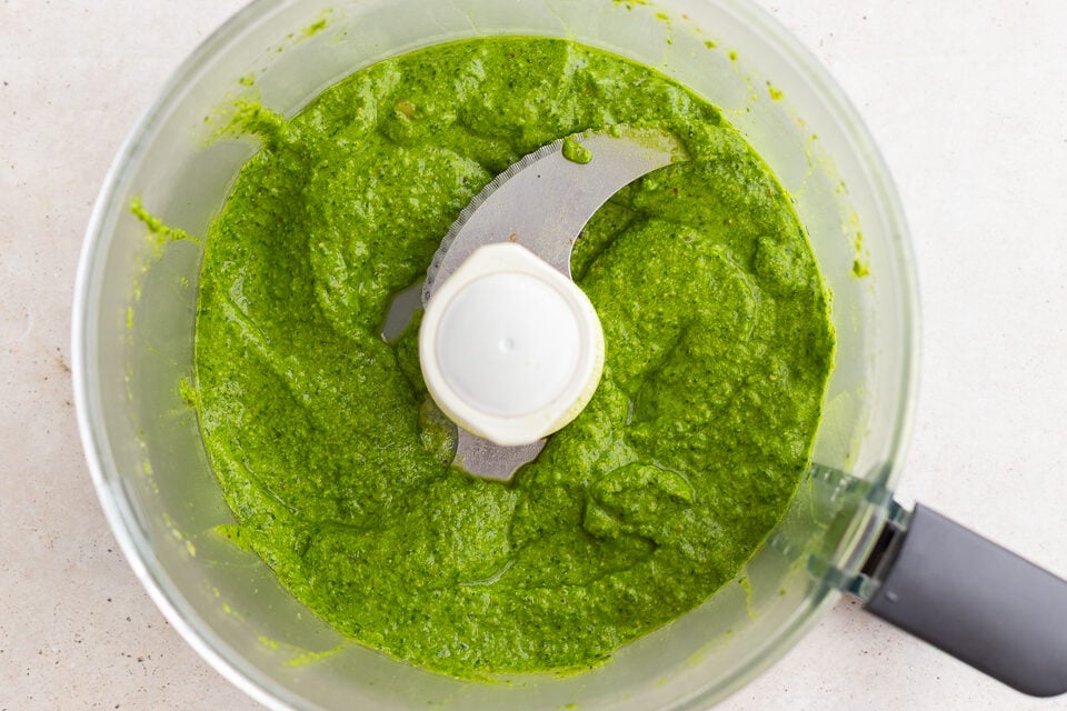 fresh homemade pesto blended up in a food processor base.