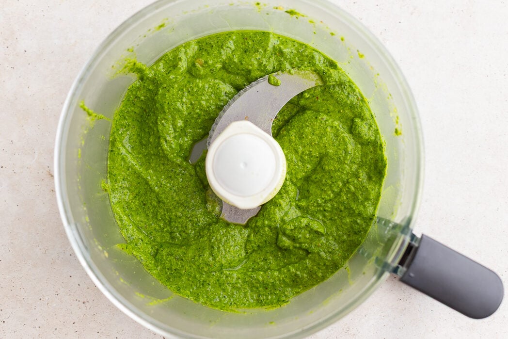 fresh homemade pesto blended up in a food processor base.