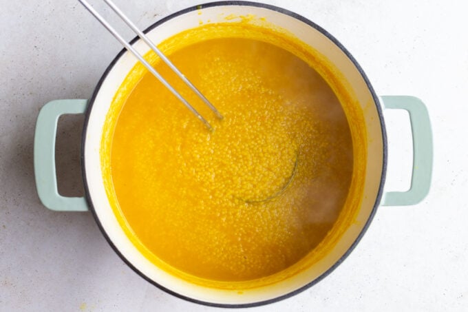 italian penicillin pastina soup in a large pot with a ladle pulling up soup
