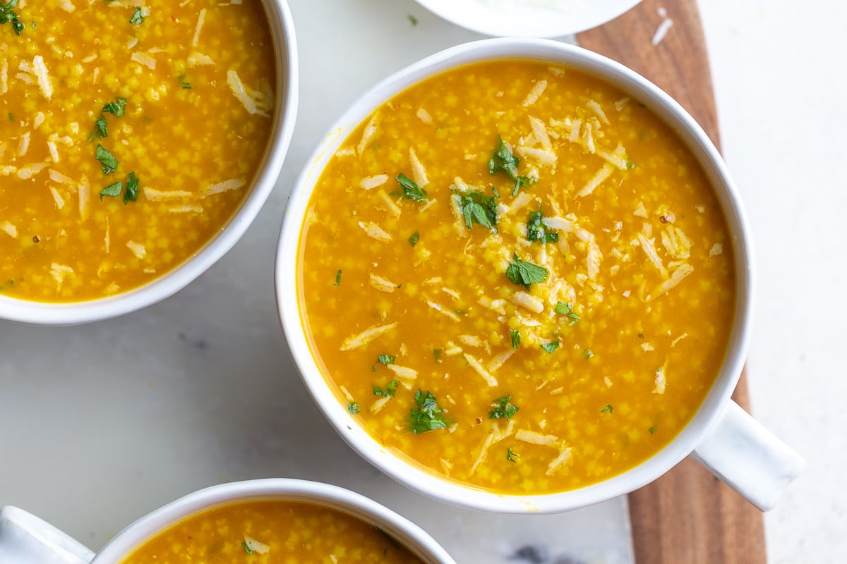 italian penicillin soup in soup bowls topped with chopped parsley and shredded parmesan cheese