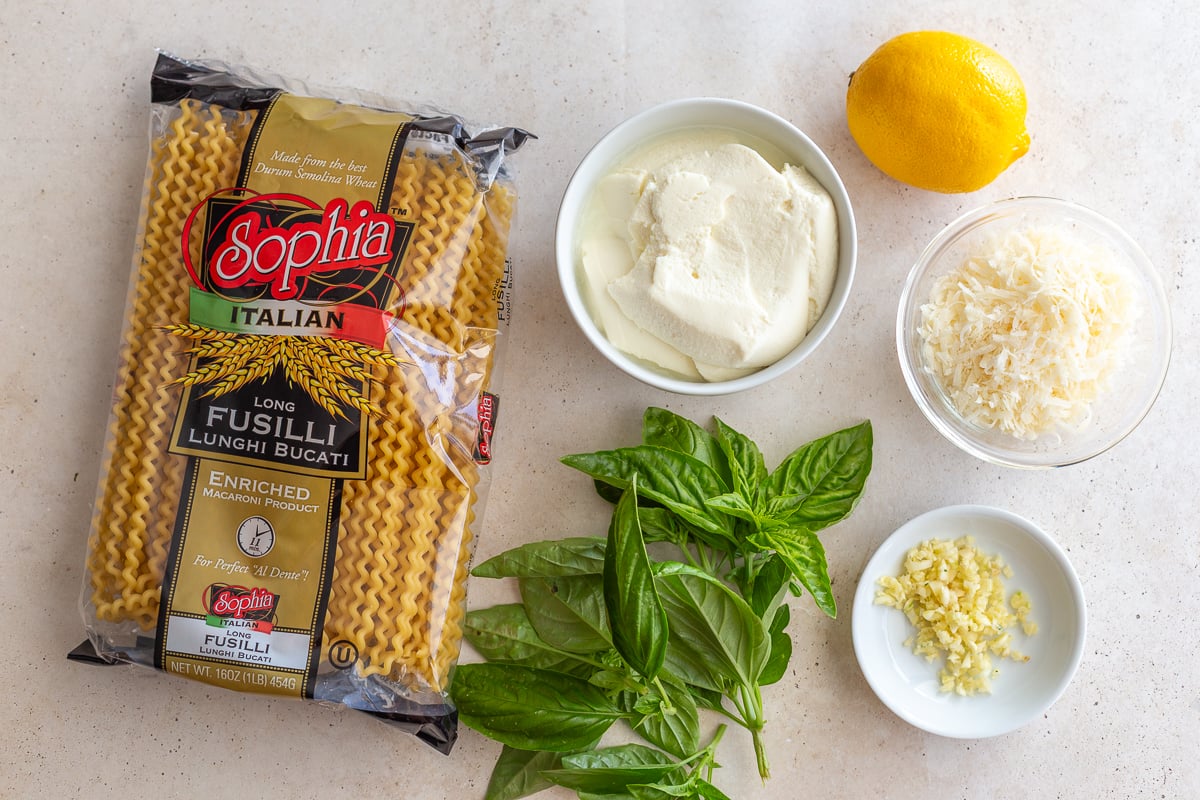 ingredients needed to make ricotta pasta including pasta, basil, ricotta, lemon, parmesan, and garlic